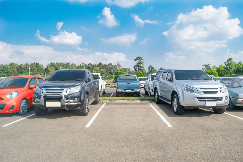 Cars,Parking,In,Asphalt,Parking,Lot.,Trees,,White,Cloud,Blue