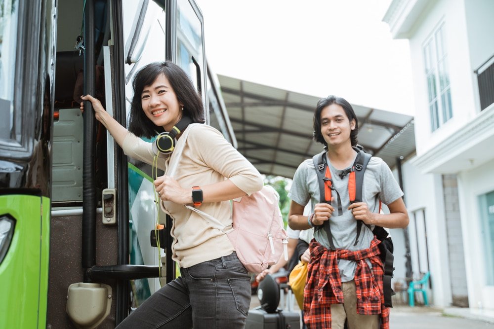 A,Smiling,Woman,Carrying,A,Backpack,And,Headphones,While,Holding